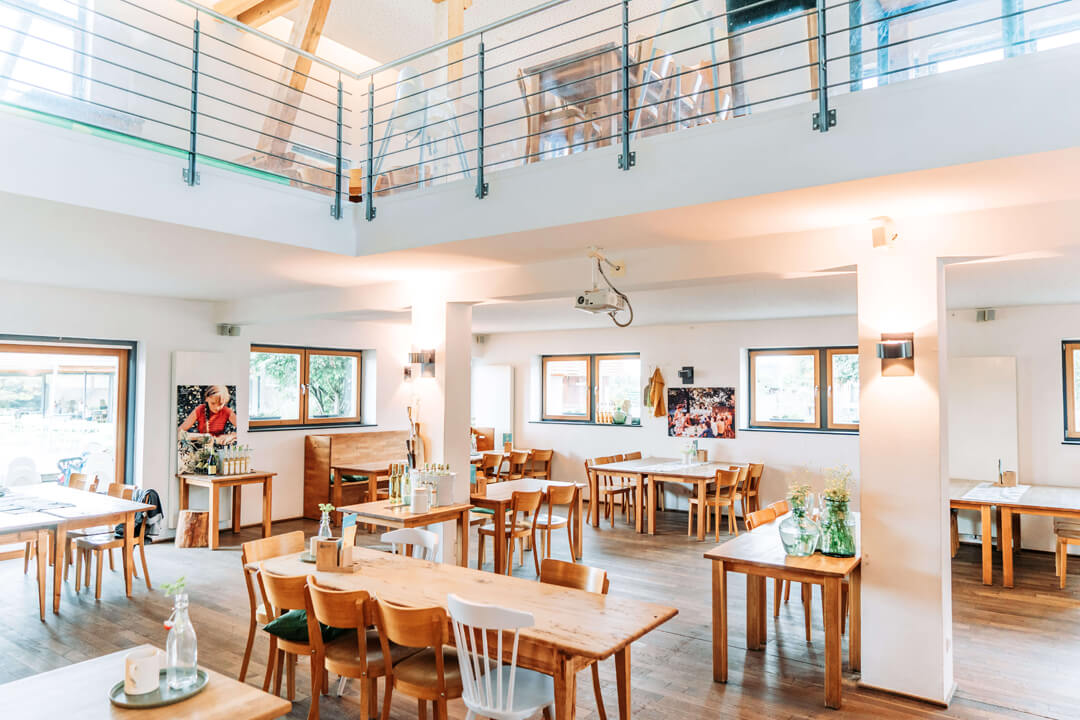 Salle de restaurant lumineuse avec tables en bois au Gut Hügle